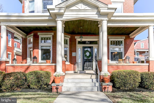 entrance to property featuring brick siding and a porch