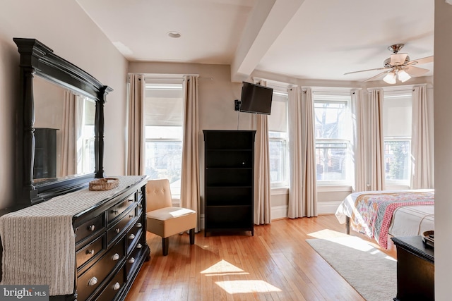 bedroom featuring light wood-type flooring, beamed ceiling, and ceiling fan