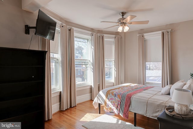 bedroom with a ceiling fan, baseboards, and light wood-type flooring