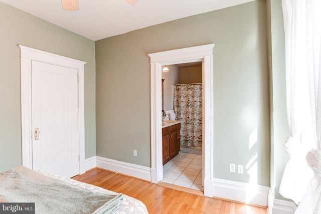 bedroom with ensuite bath, baseboards, and light wood-style floors