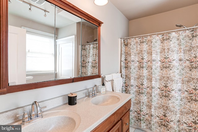 full bathroom featuring double vanity, track lighting, a shower with shower curtain, and a sink