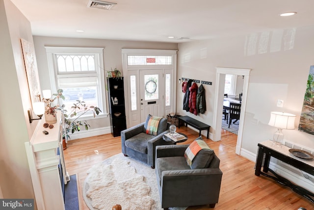 living area with plenty of natural light, light wood-style floors, and visible vents