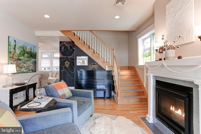 living room with visible vents, plenty of natural light, stairs, and a fireplace with flush hearth