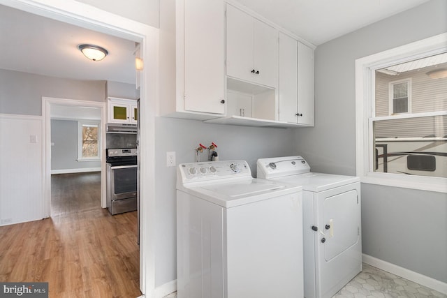 washroom featuring washer and dryer, cabinet space, baseboards, and light wood-type flooring