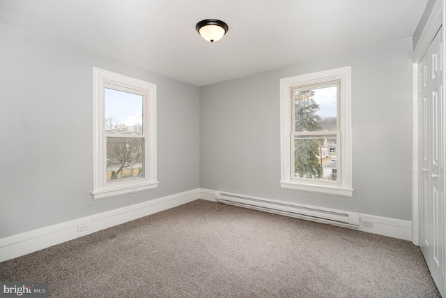 carpeted empty room with a baseboard heating unit and baseboards