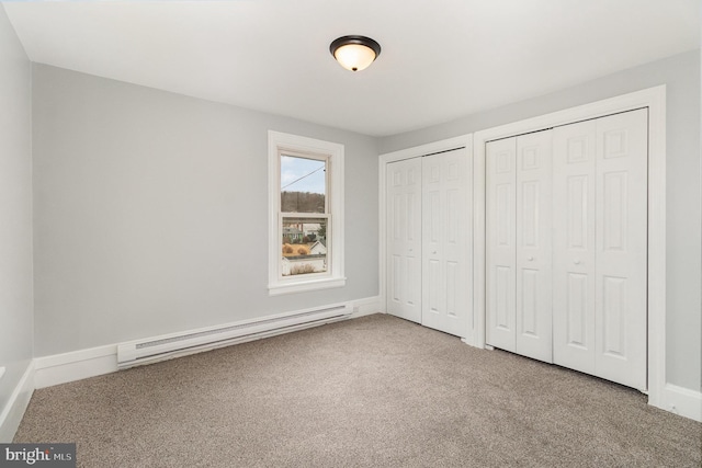 unfurnished bedroom with a baseboard heating unit, multiple closets, baseboards, and carpet flooring