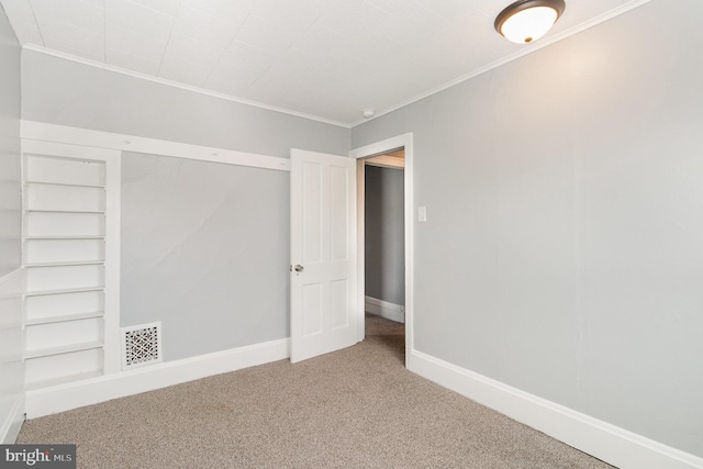 unfurnished bedroom with crown molding, carpet flooring, visible vents, and baseboards