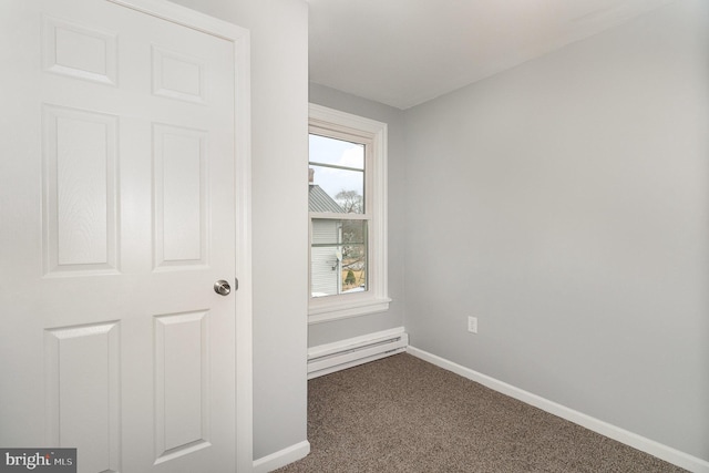 spare room with dark colored carpet, baseboards, and baseboard heating