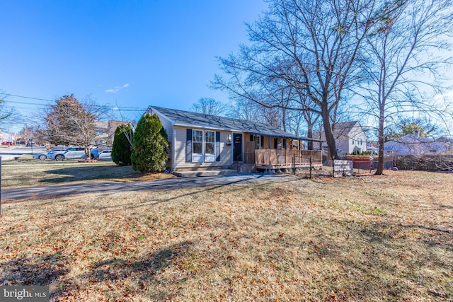 view of front facade featuring a porch, a front lawn, and fence