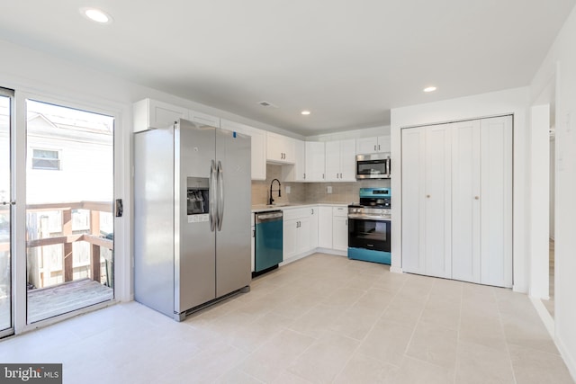 kitchen with a sink, tasteful backsplash, white cabinetry, appliances with stainless steel finishes, and light countertops