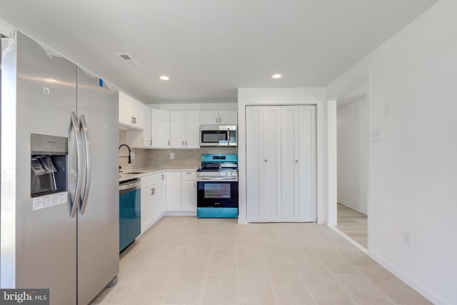 kitchen featuring visible vents, stainless steel appliances, light countertops, white cabinetry, and backsplash