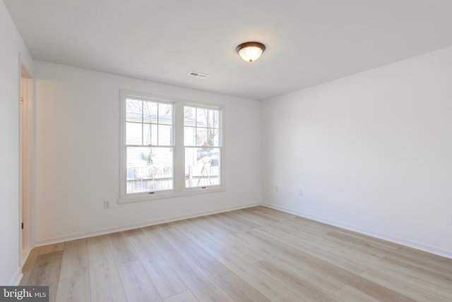 spare room with visible vents, light wood-type flooring, and baseboards