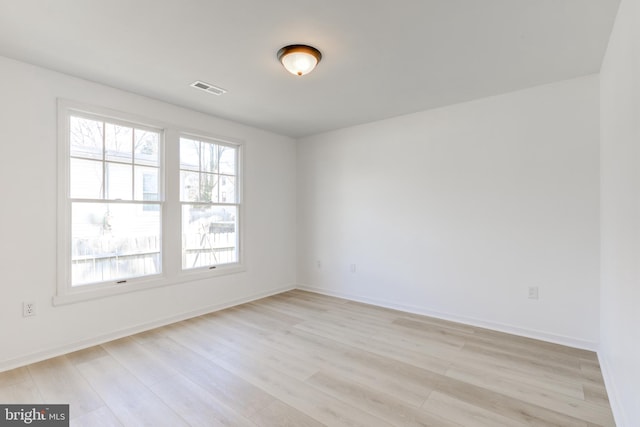 unfurnished room featuring baseboards, visible vents, and light wood-type flooring