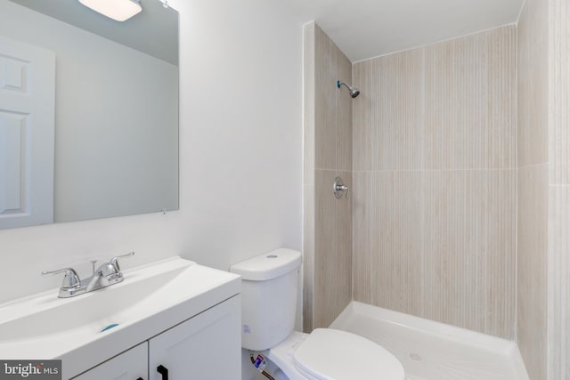 full bathroom with vanity, toilet, and tiled shower