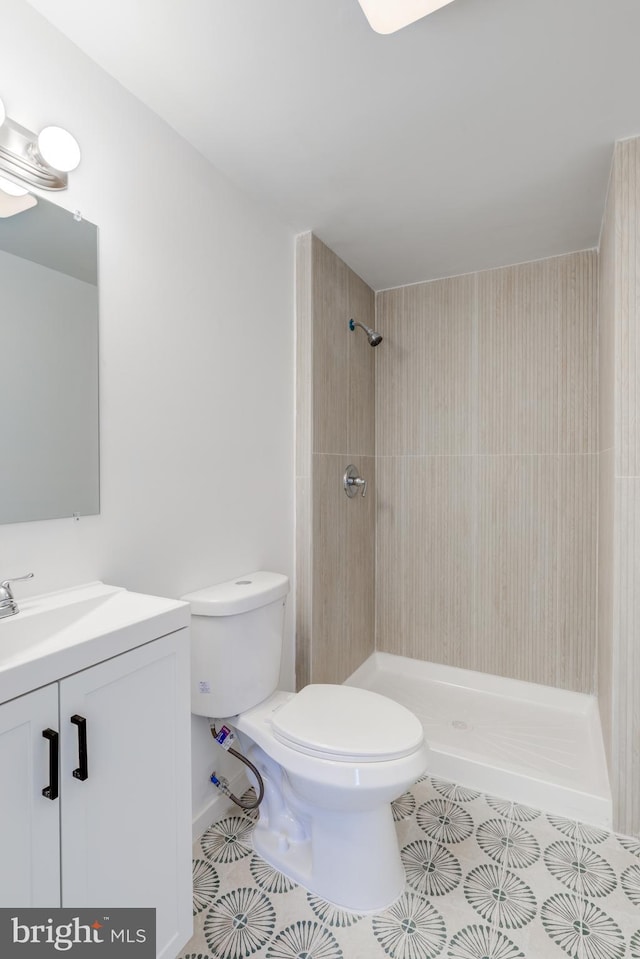 full bathroom with tile patterned floors, toilet, vanity, and a tile shower