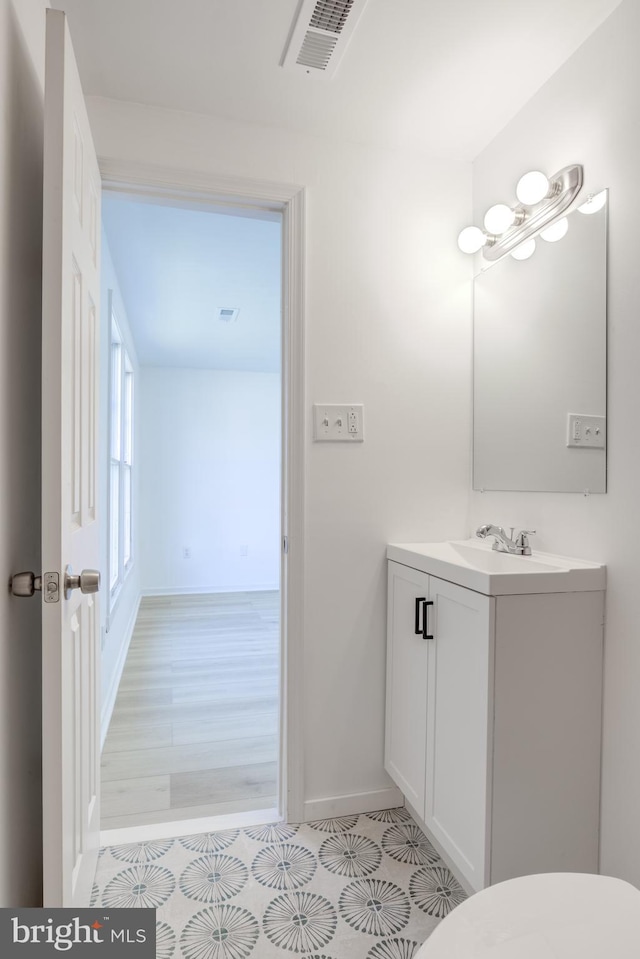 bathroom featuring visible vents, baseboards, toilet, and vanity