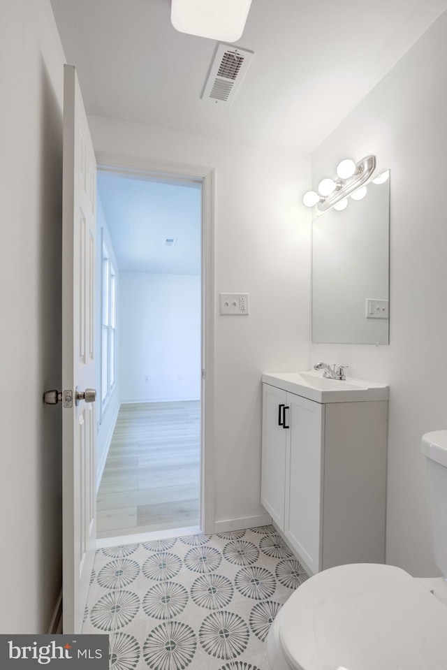 bathroom featuring vanity, toilet, baseboards, and visible vents