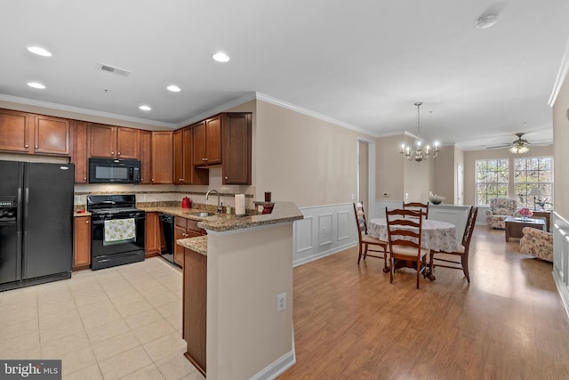 kitchen with light stone countertops, ornamental molding, a peninsula, black appliances, and a sink