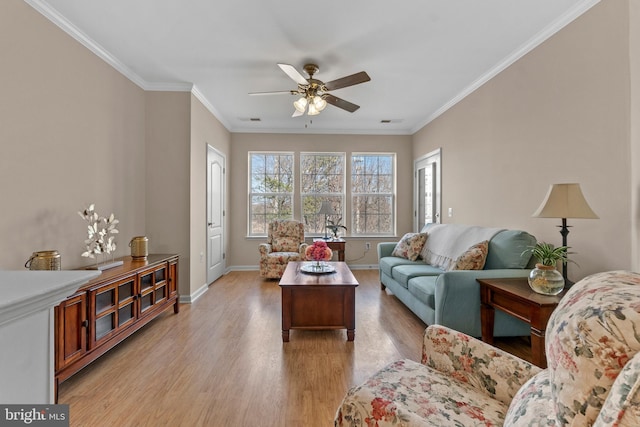 living room featuring visible vents, light wood-style flooring, a ceiling fan, crown molding, and baseboards