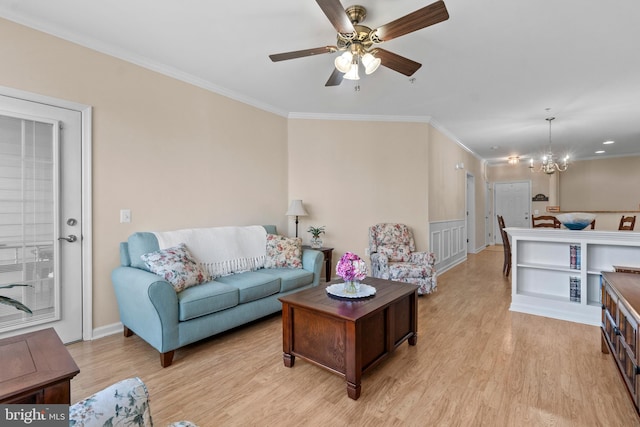 living room with ceiling fan with notable chandelier, light wood finished floors, and ornamental molding