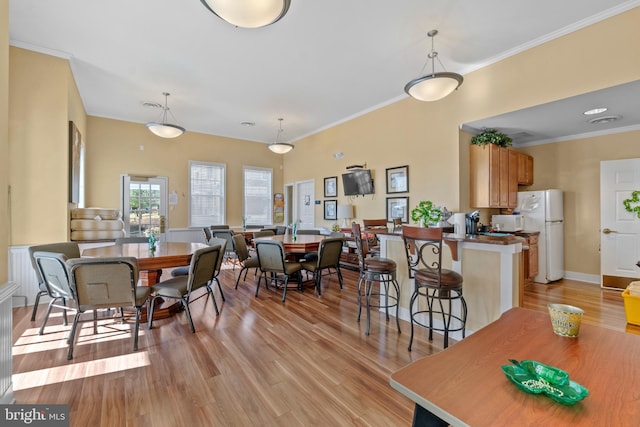 dining area featuring light wood-type flooring, baseboards, and crown molding