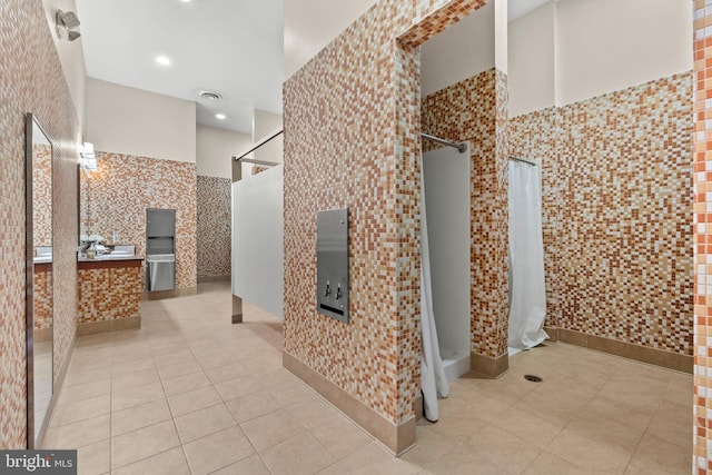 bathroom featuring visible vents, a stall shower, a high ceiling, tile walls, and tile patterned flooring