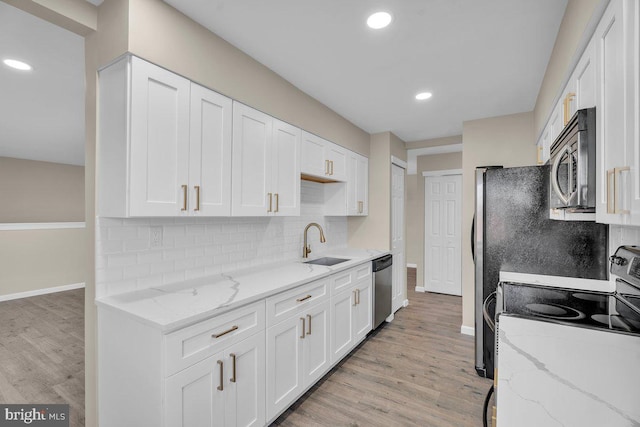 kitchen with a sink, stainless steel appliances, light wood-style floors, and white cabinetry