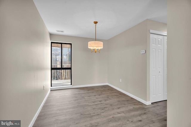 unfurnished room with visible vents, baseboards, and wood finished floors