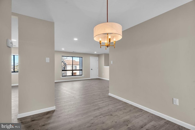 interior space with a wealth of natural light, baseboards, an inviting chandelier, and dark wood-style flooring