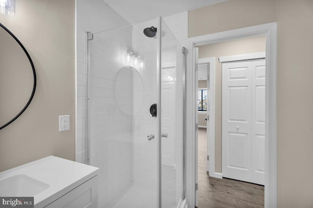 full bath with vanity, wood finished floors, and a shower stall