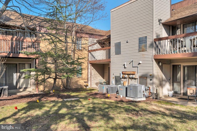 back of property featuring a lawn and cooling unit