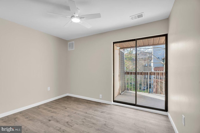 spare room featuring visible vents, ceiling fan, baseboards, and wood finished floors