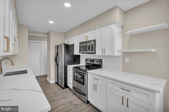 kitchen featuring a sink, decorative backsplash, stainless steel appliances, white cabinetry, and open shelves