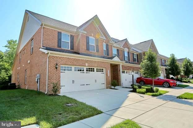 view of front of property with a front yard, brick siding, a garage, and driveway