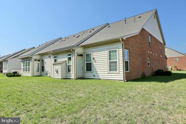 rear view of property with brick siding and a lawn