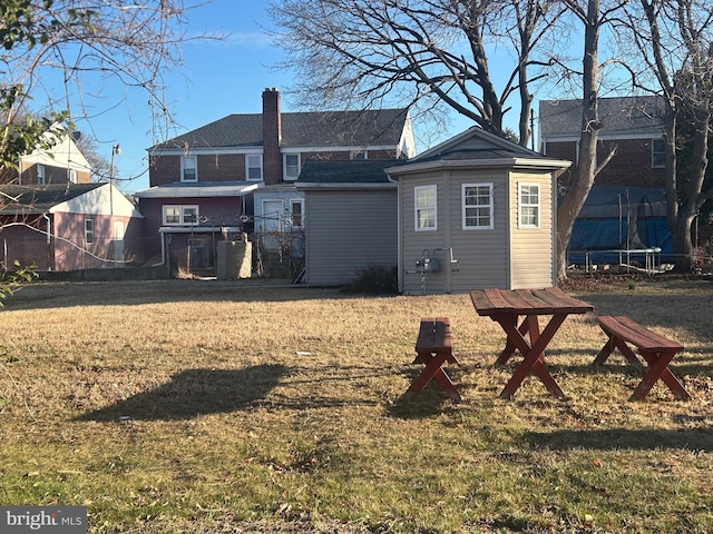 rear view of property with central air condition unit, a lawn, fence, an outdoor structure, and a chimney