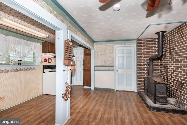 kitchen featuring ceiling fan, wood finished floors, a wood stove, and wallpapered walls