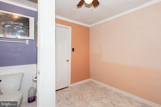 bathroom featuring toilet, marble finish floor, crown molding, baseboards, and ceiling fan