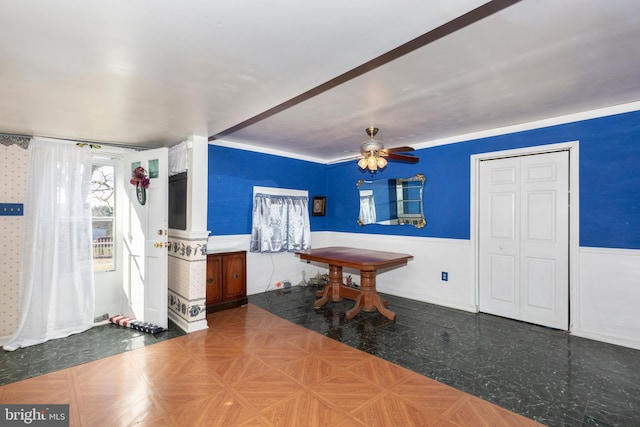 dining area featuring a ceiling fan and a wainscoted wall