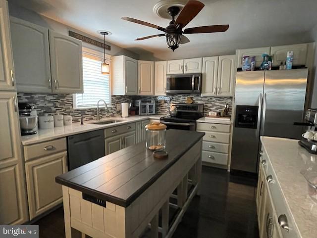 kitchen featuring a sink, decorative backsplash, appliances with stainless steel finishes, and decorative light fixtures