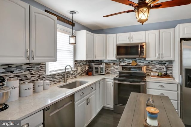 kitchen with a sink, decorative light fixtures, tasteful backsplash, appliances with stainless steel finishes, and white cabinets