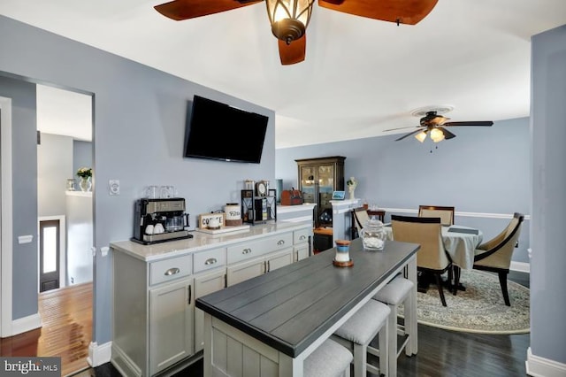 kitchen with dark wood finished floors, baseboards, and ceiling fan