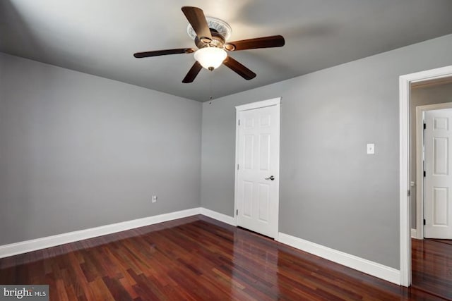 empty room featuring baseboards, ceiling fan, and dark wood-style flooring