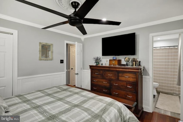 bedroom with ensuite bath, wood finished floors, a wainscoted wall, and ornamental molding