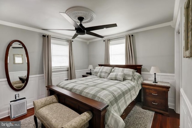 bedroom with ceiling fan, ornamental molding, dark wood-style flooring, and wainscoting