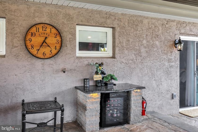 exterior details featuring a fire extinguisher, wine cooler, a bar, and stucco siding