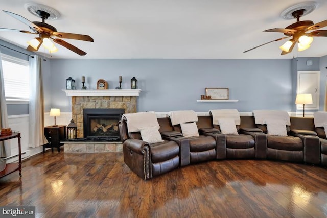 interior space with a stone fireplace, wood finished floors, and a ceiling fan