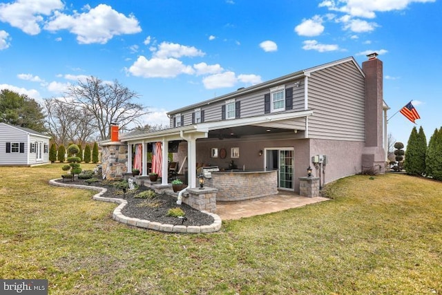 rear view of property featuring outdoor dry bar, a lawn, stucco siding, a chimney, and a patio area