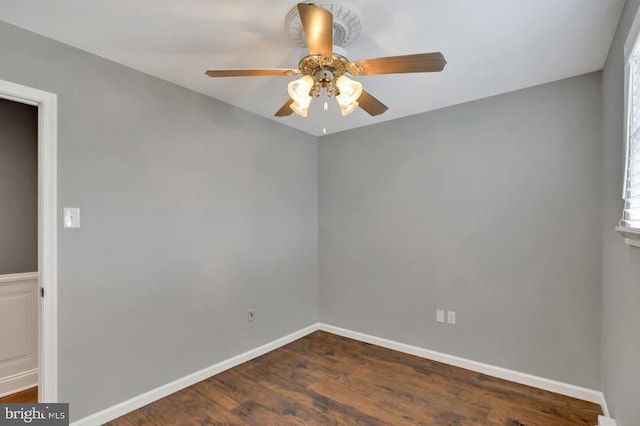 spare room featuring dark wood-style floors, ceiling fan, and baseboards