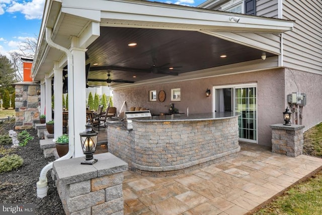 view of patio with an outdoor kitchen, outdoor wet bar, grilling area, and ceiling fan